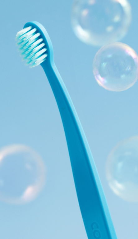 Blue toothbrush with bristles against a light blue background with bubbles